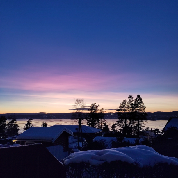 A pink and violet sunset over a fjord.