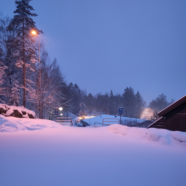 A street at dusk covered with an untouched layer of snow.