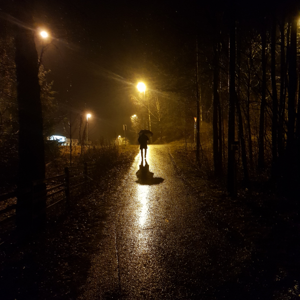 Silhouette of a person with an umbrella in the rain.