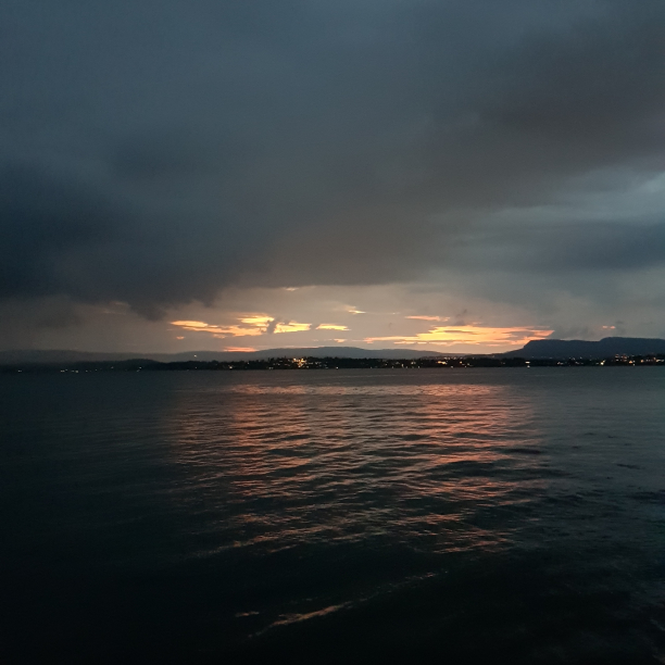 A beer by the fjord. Not pictured: Beer. An light yellow sunset over the fjord.