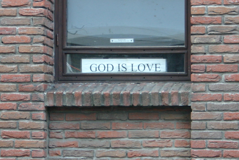 A sign in a window. The sign says &ldquo;GOD IS LOVE&rdquo; in capital letters.