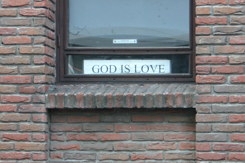 A sign in a window. The sign says “GOD IS LOVE” in capital letters.